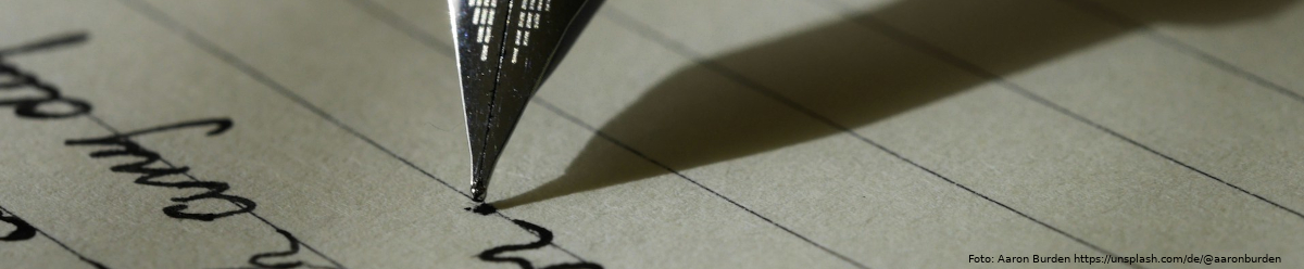 Nahaufnahme einer Füllfederhalterspitze, die mit schwarzer Tinte auf ein Blatt Papier schreibt.